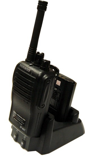 A black walkie talkie is sitting on the ground.