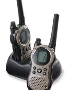 Two walkie talkies sitting on top of a black holder.